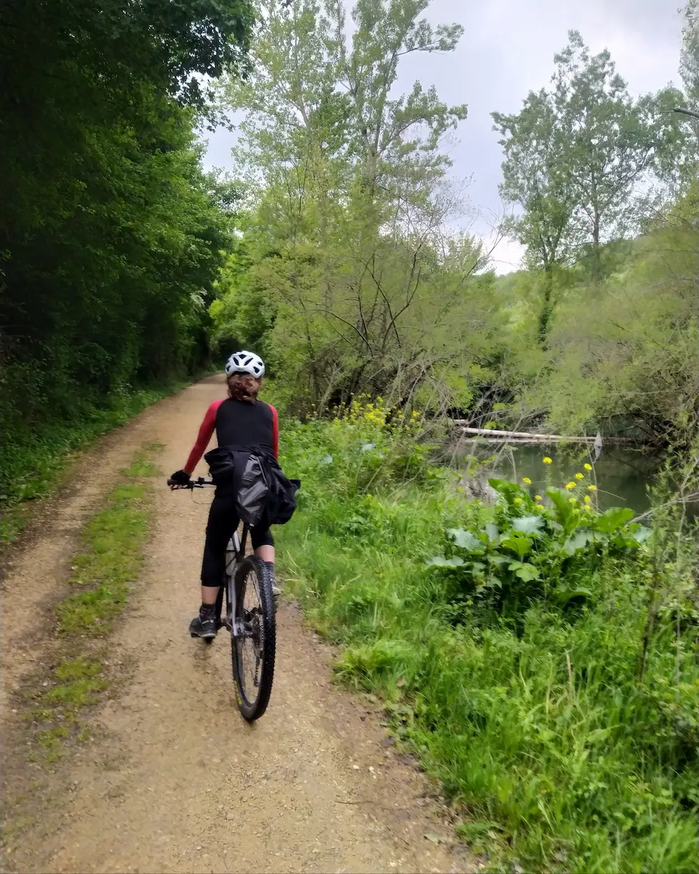 Mujer ciclista pedaleando por la vía verde del vasco navarro en una ruta con rodando en verde