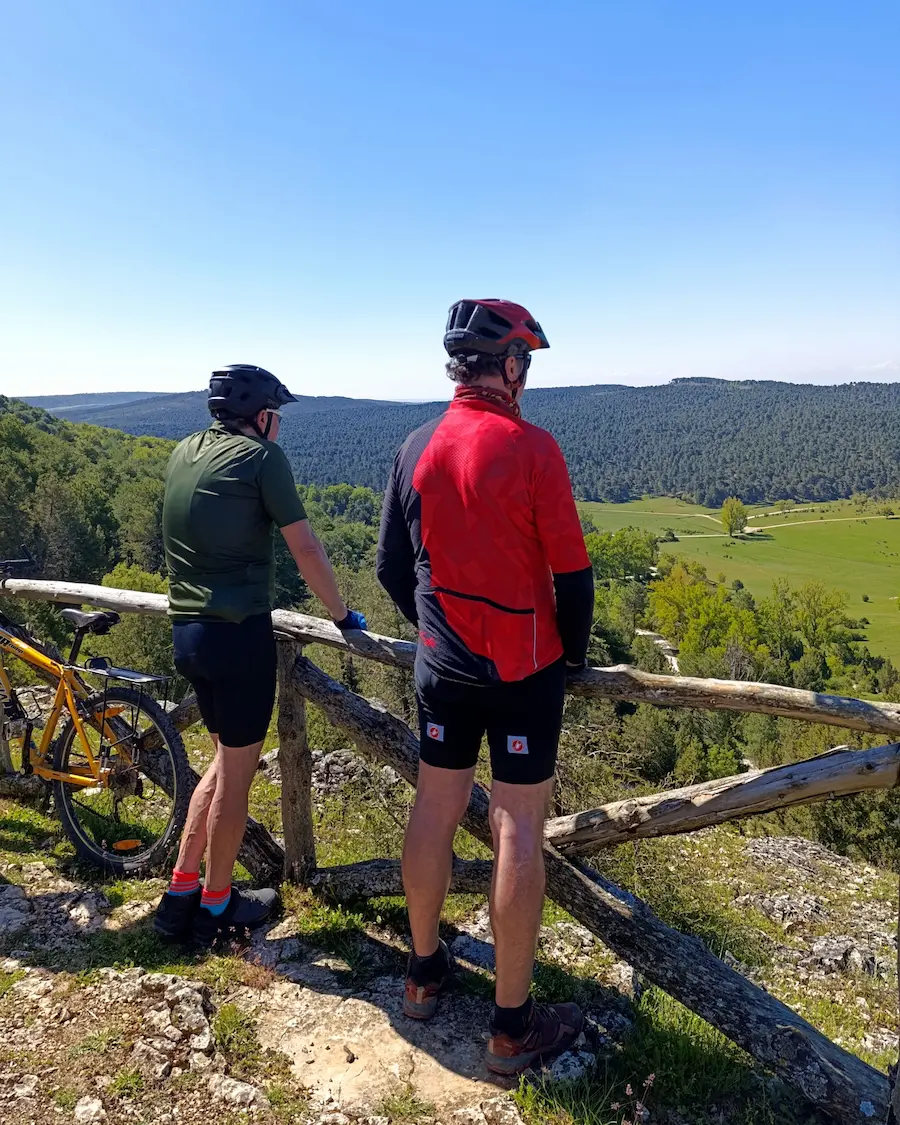 Dos ciclistas disfrutan contemplando el paisaje en una ruta en bicicleta en Tierra de Pinares organizada por Rodando en verde